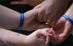 People holding hands while wearing blue RAINN wristbands